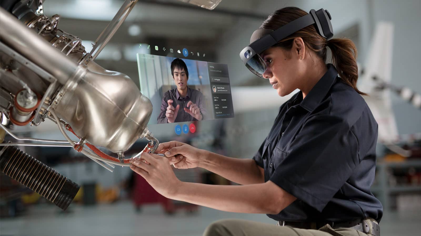 A worker wears AR Goggles while receiving help from a coworker